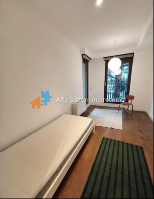 Small bedroom with a bed and wooden floor.