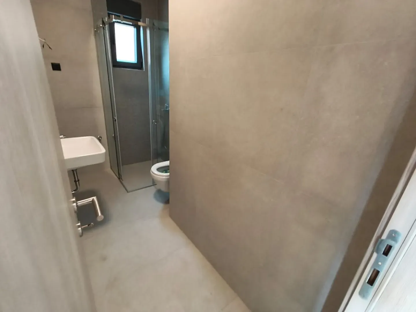 Moderne pločice i tuš kabina u kupatilu sa umivaonikom.