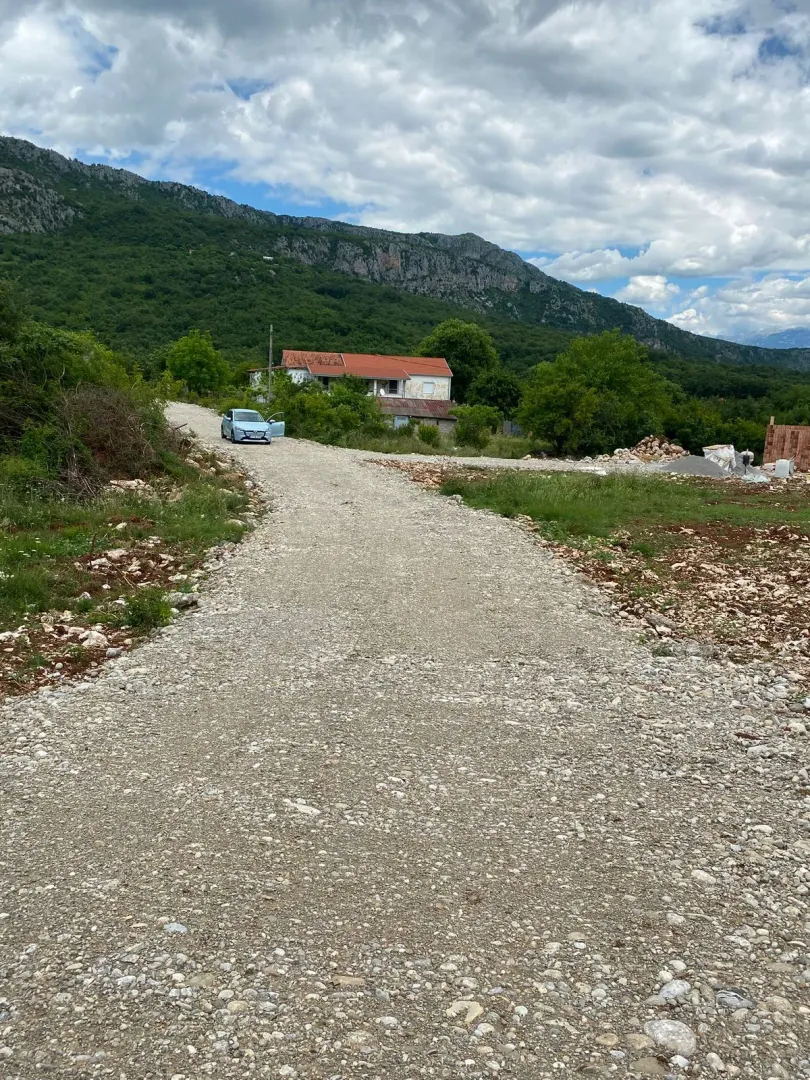Makadamski put koji vodi prema kući u prirodi.
