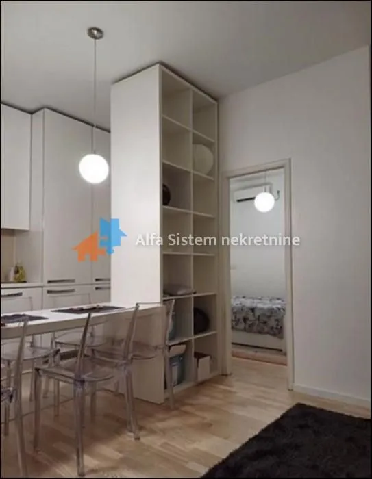 Trpezarija sa trpezarijskim stolom i stolicama, povezana sa kuhinjom.