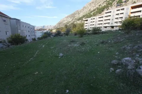 Travnati plac za gradnju okružen stambenim zgradama i brdima u pozadini. - image 17