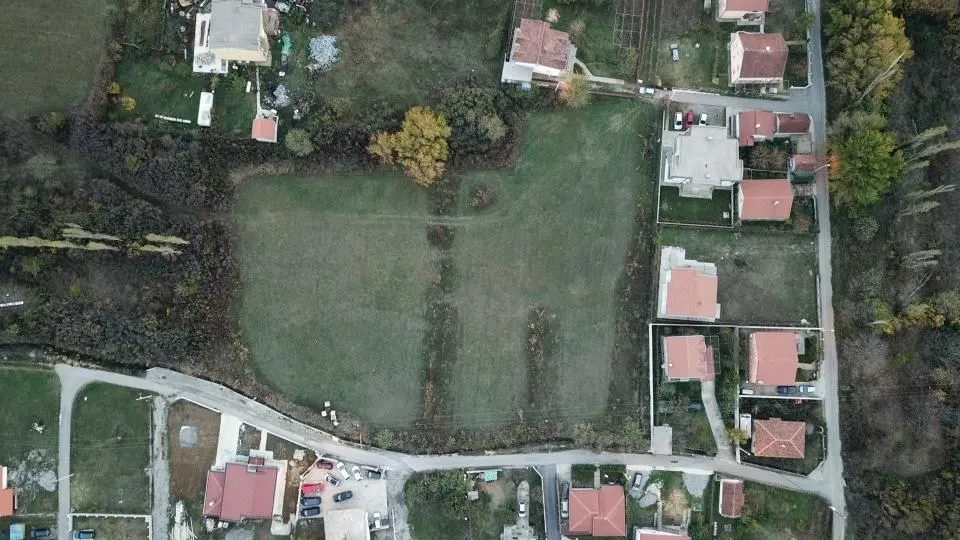 Pogled iz vazduha na građevinsko zemljište sa okolnim kućama i pristupnim putem.