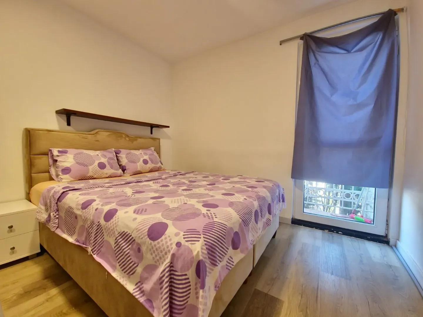 Spavaća soba sa bračnim krevetom i prozorom koji gleda spolja.