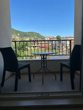 Furnished balcony with a table, chairs, and a view of the settlement and surrounding hills. - image 9