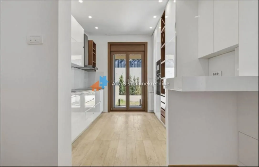 Modern white kitchen with wooden details and access to the courtyard.