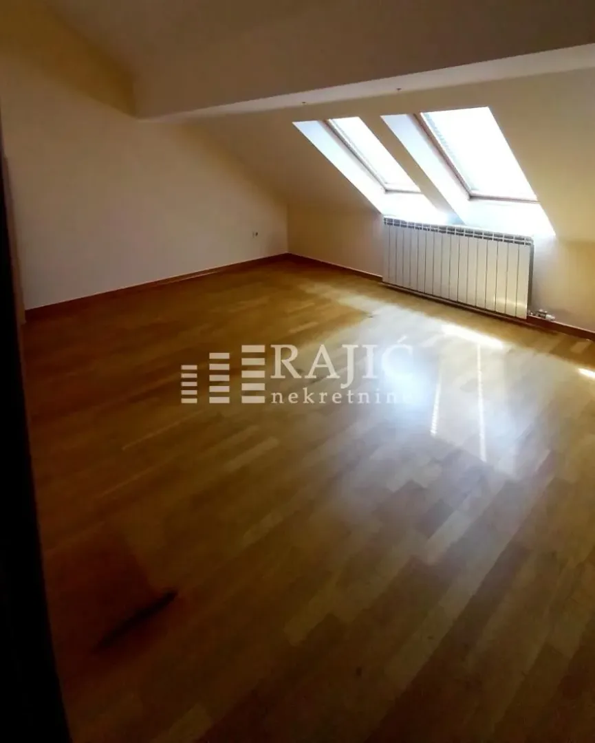 Empty attic room with wooden flooring and roof windows.