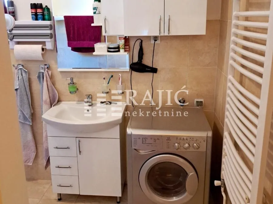 Smaller bathroom with a sink, cabinet, and washing machine.