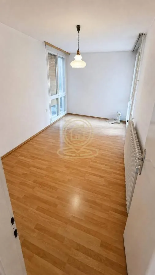 Prazna soba sa laminatom i belim zidovima.