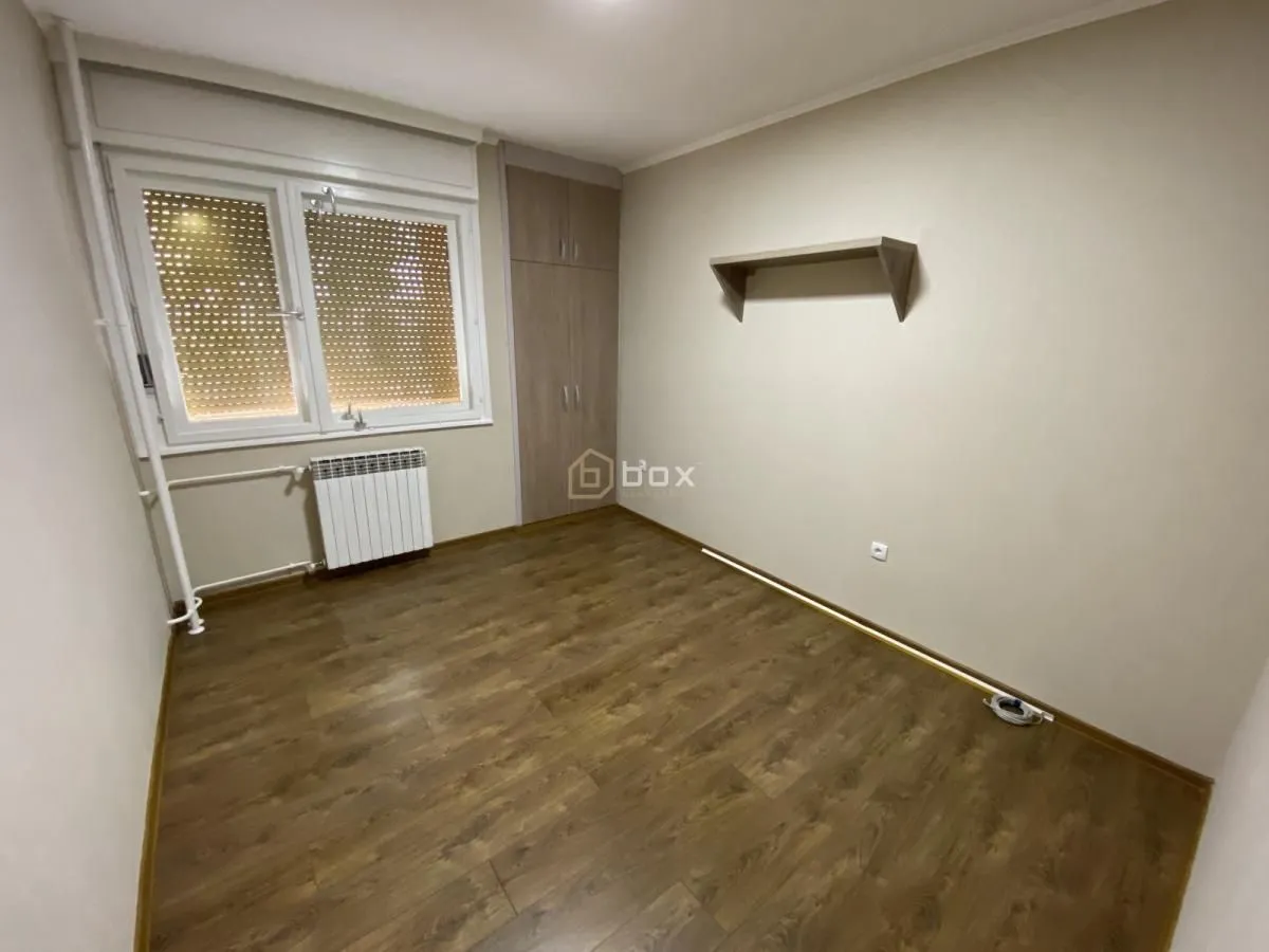 Empty room with laminate flooring, a window, and a built-in wardrobe.