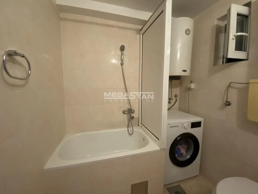 Bathroom with bathtub, shower, water heater, and washing machine.