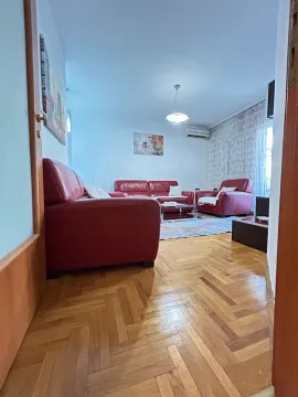 Dnevna soba sa crvenim kožnim garniturama i drvenim parketom. - image 7
