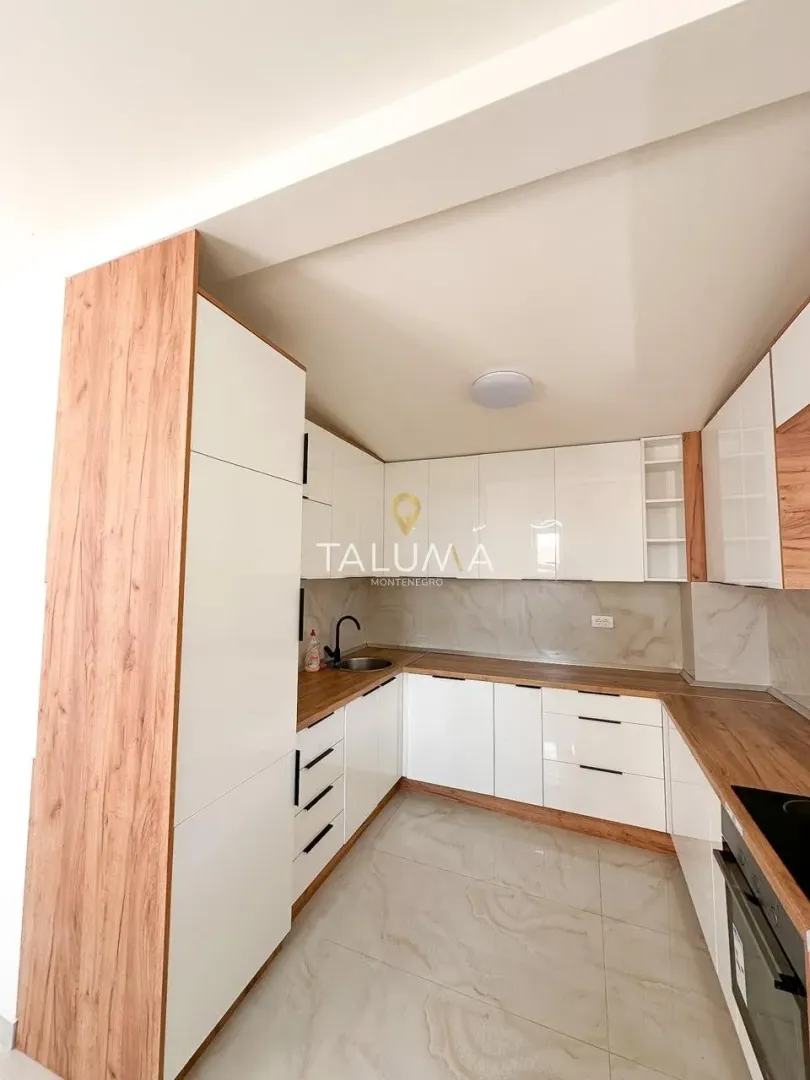 Modern kitchen with white units and wooden countertops.