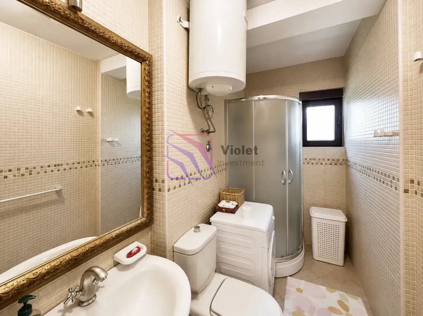 Bathroom equipped with a shower cabin, sink, toilet, and washing machine.