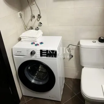 View of the bathroom with a washing machine and toilet. - image 12