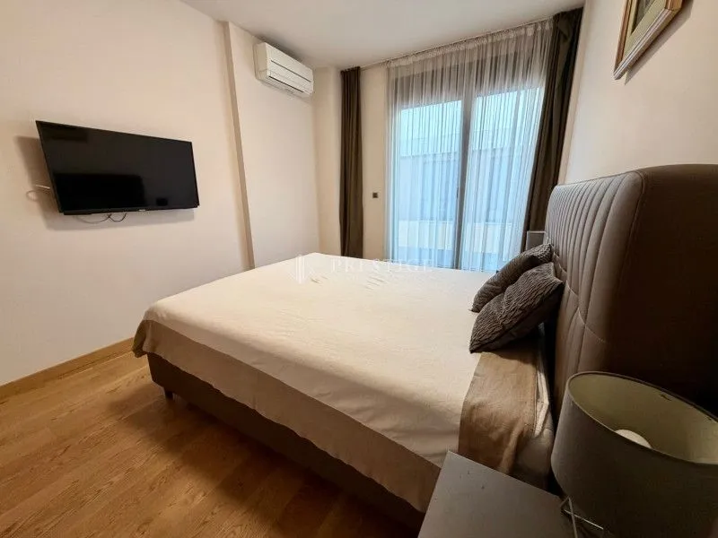 Furnished bedroom with a double bed and a wall-mounted TV.