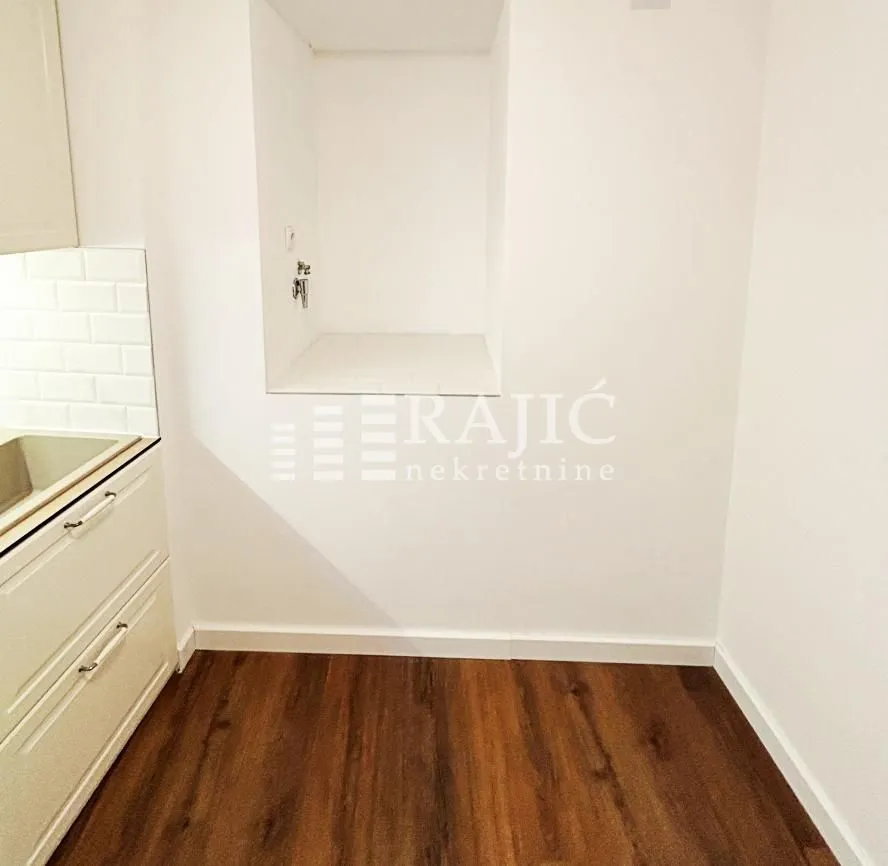 Part of the kitchen with white cabinetry and laminate flooring.