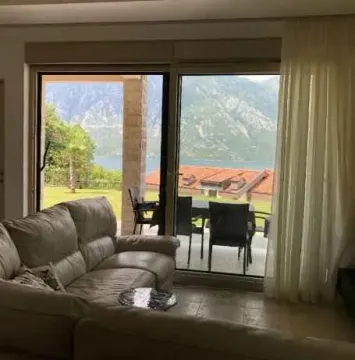 Dnevna soba sa udobnom garniturom i panoramskim pogledom na more i planine kroz staklena vrata. - image 2