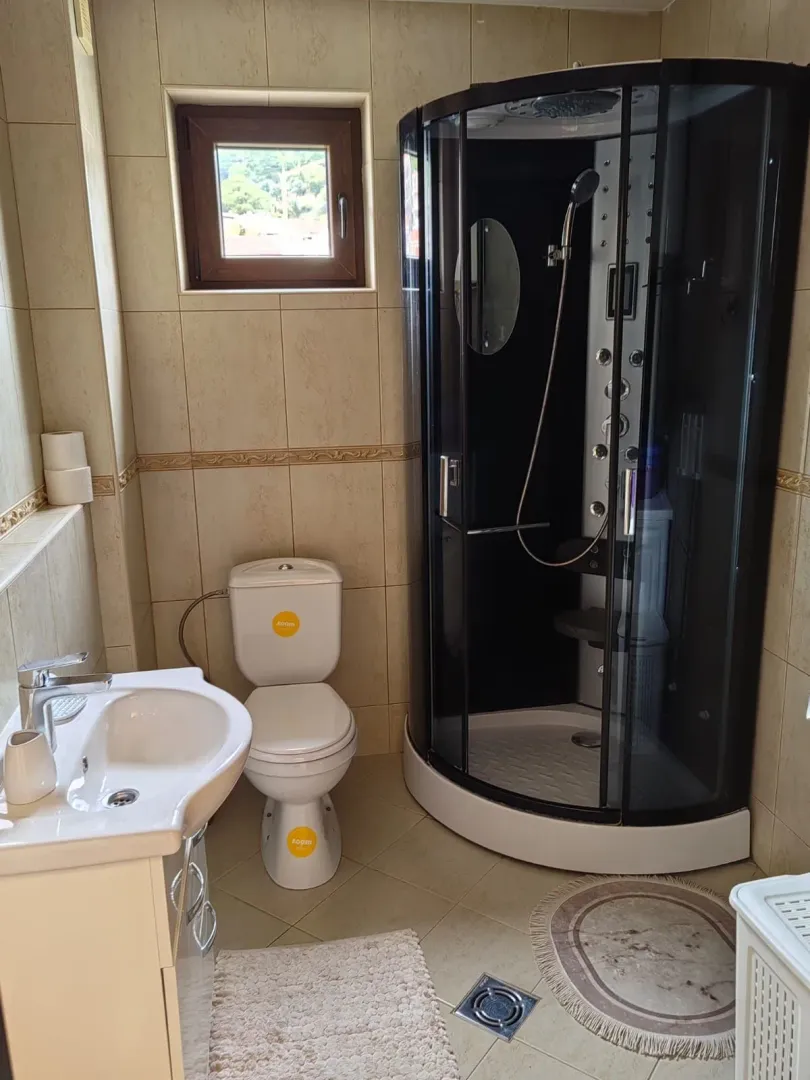 Fully equipped bathroom with a shower cabin, sink, and toilet.