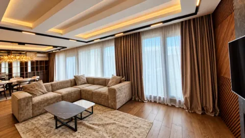 Modern living room with a sectional sofa, large windows, and a drop ceiling with lighting. - image 10
