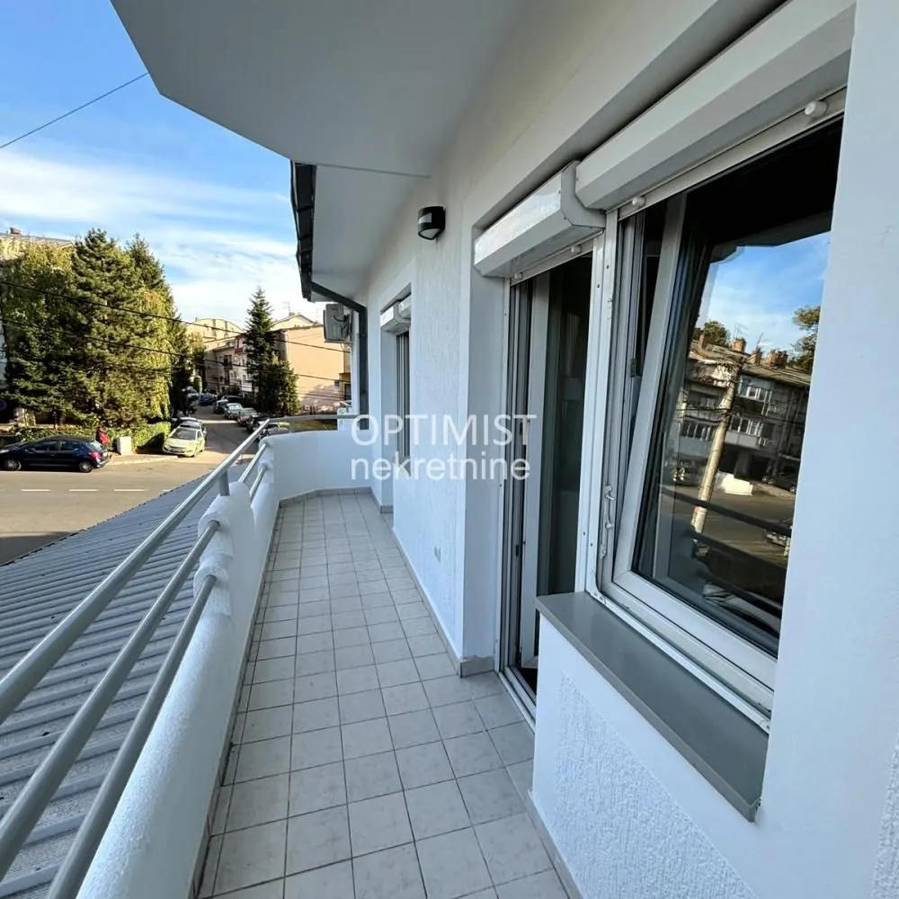 Dugačak popločani balkon sa metalnom ogradom i pogledom na ulicu.