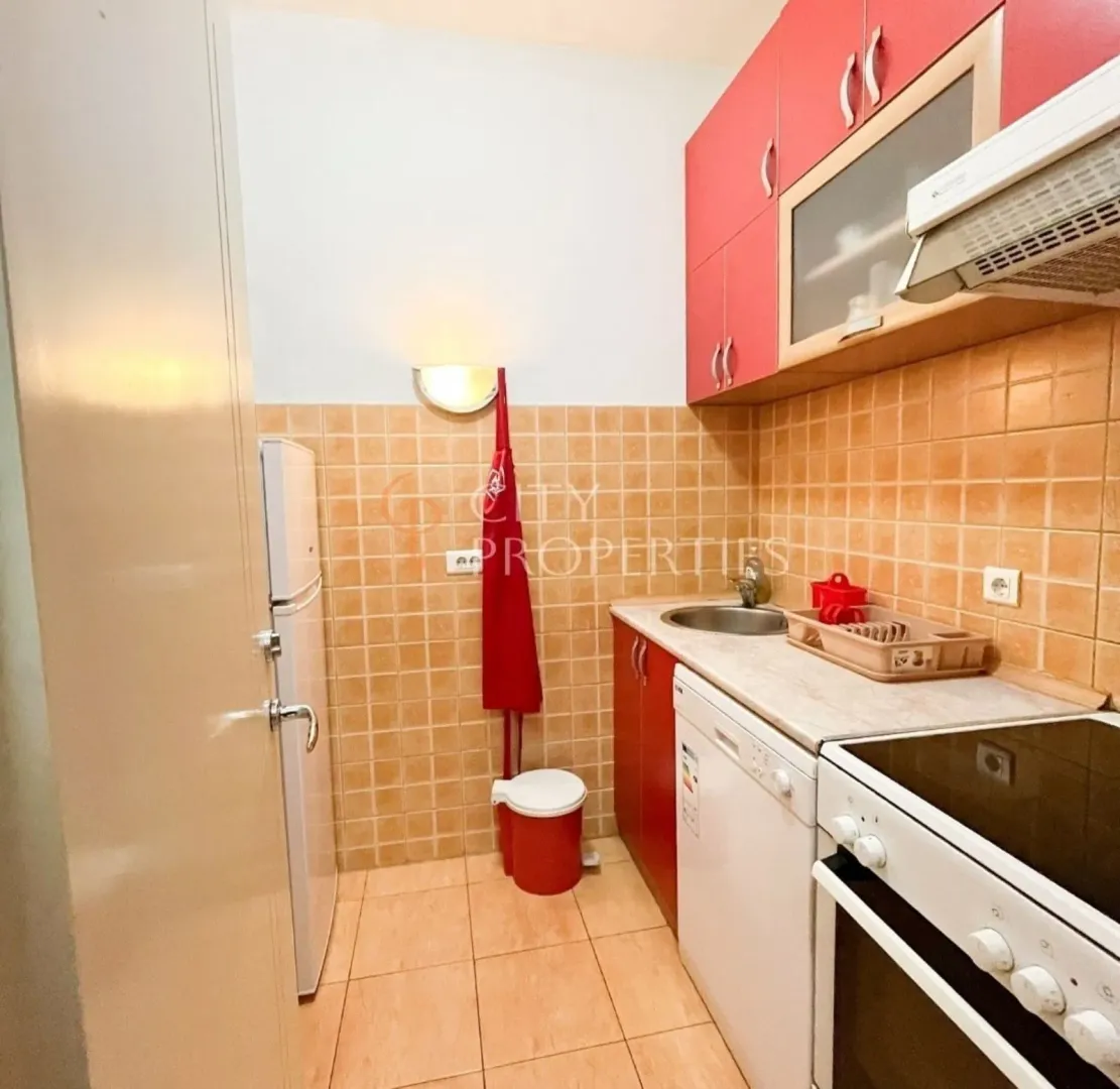 A functional kitchen with red cabinets and white appliances.