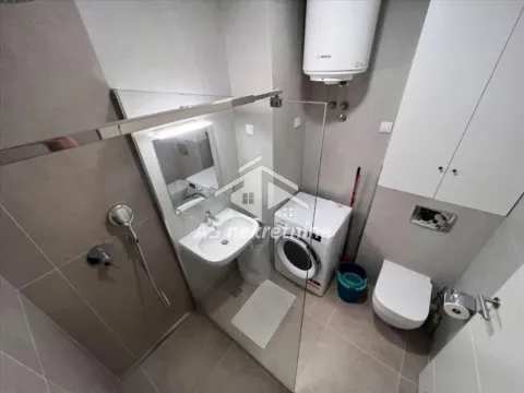 Modern bathroom with a walk-in shower, washbasin, washing machine, and toilet. - image 9