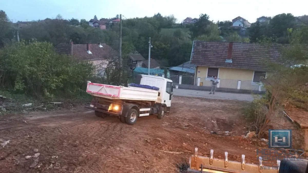 Kamion na zemljanom putu ispred kuće u seoskom okruženju.