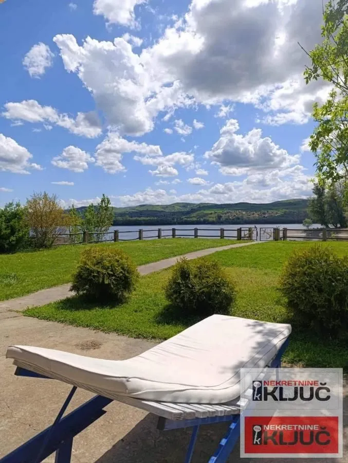 View of the lake and grassy yard with a sun lounger.