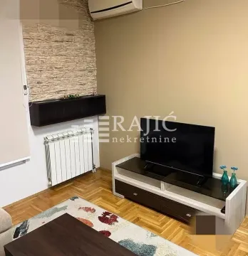 Living room with a TV unit, parquet flooring, and an accent wall. - image 5