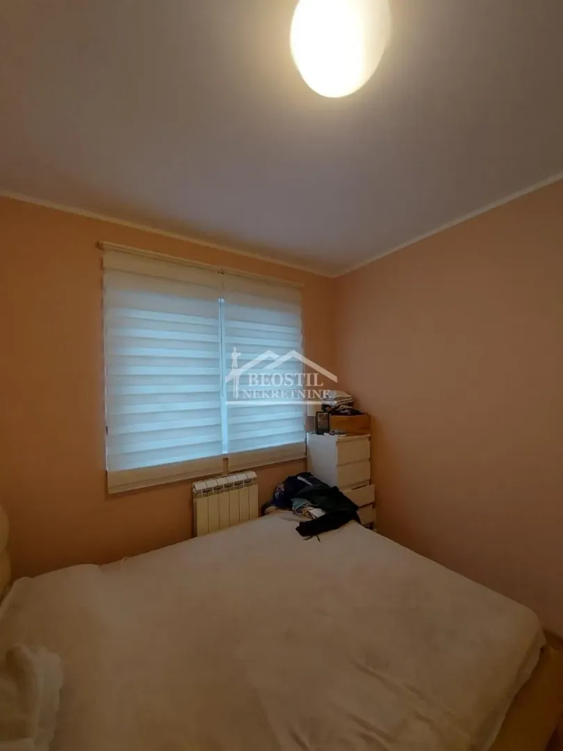 View of the bedroom with a double bed and a window with blinds.