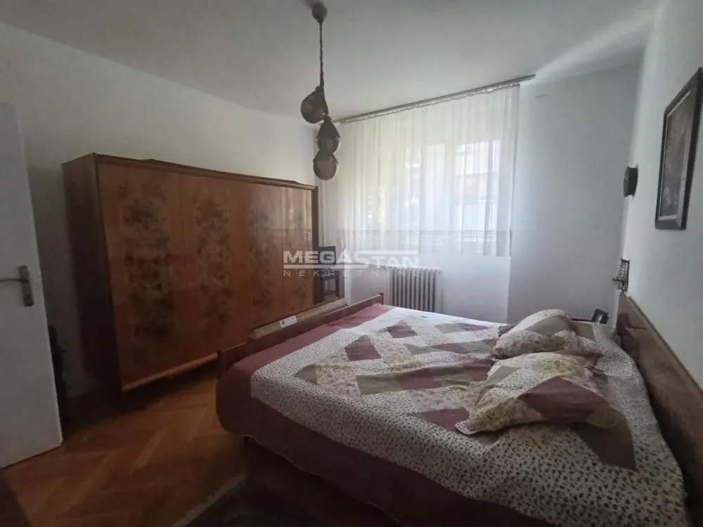 Furnished bedroom with a double bed and a wooden wardrobe.