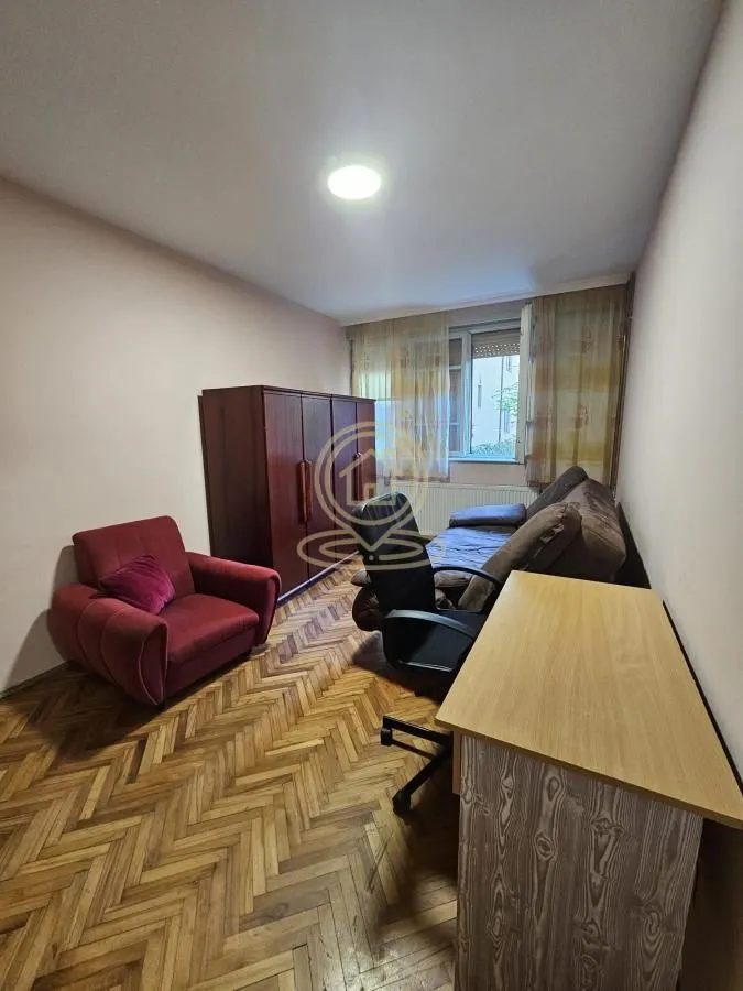 Dnevna soba sa garniturom, foteljom, radnim stolom i parketom.