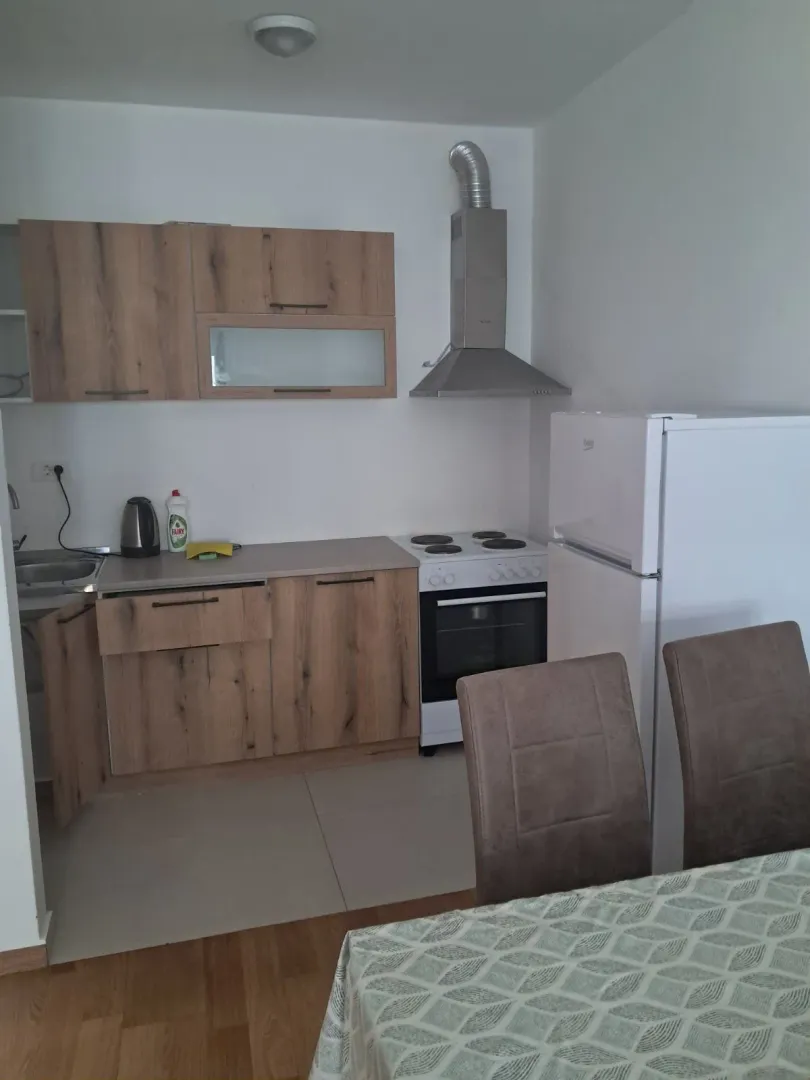 Manja kuhinja sa drvenim elementima i trpezarijskim stolom.