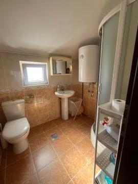 Small bathroom with a shower cabin, washbasin, and toilet in beige tones. - image 5