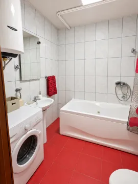 Smaller bathroom with a bathtub, washbasin, and washing machine. - image 6