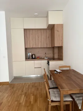 Smaller kitchen in light tones with wooden elements and a dining table. - image 3