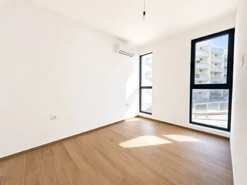 Prazna soba sa bijelim zidovima, drvenim podom i klima uređajem. - image 10