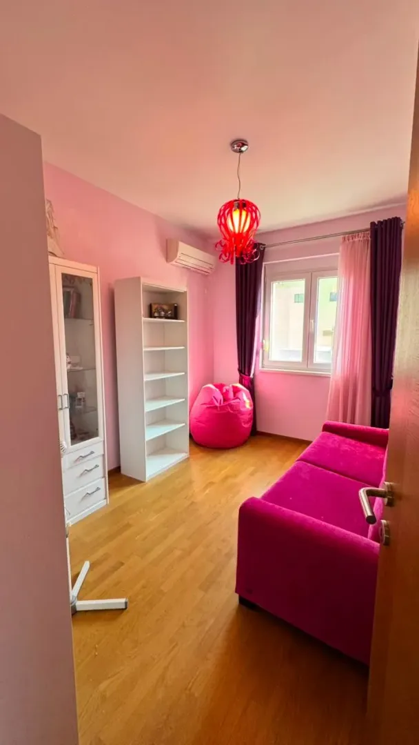 Dječja soba sa roze kaučem, policama i radnim stolom.