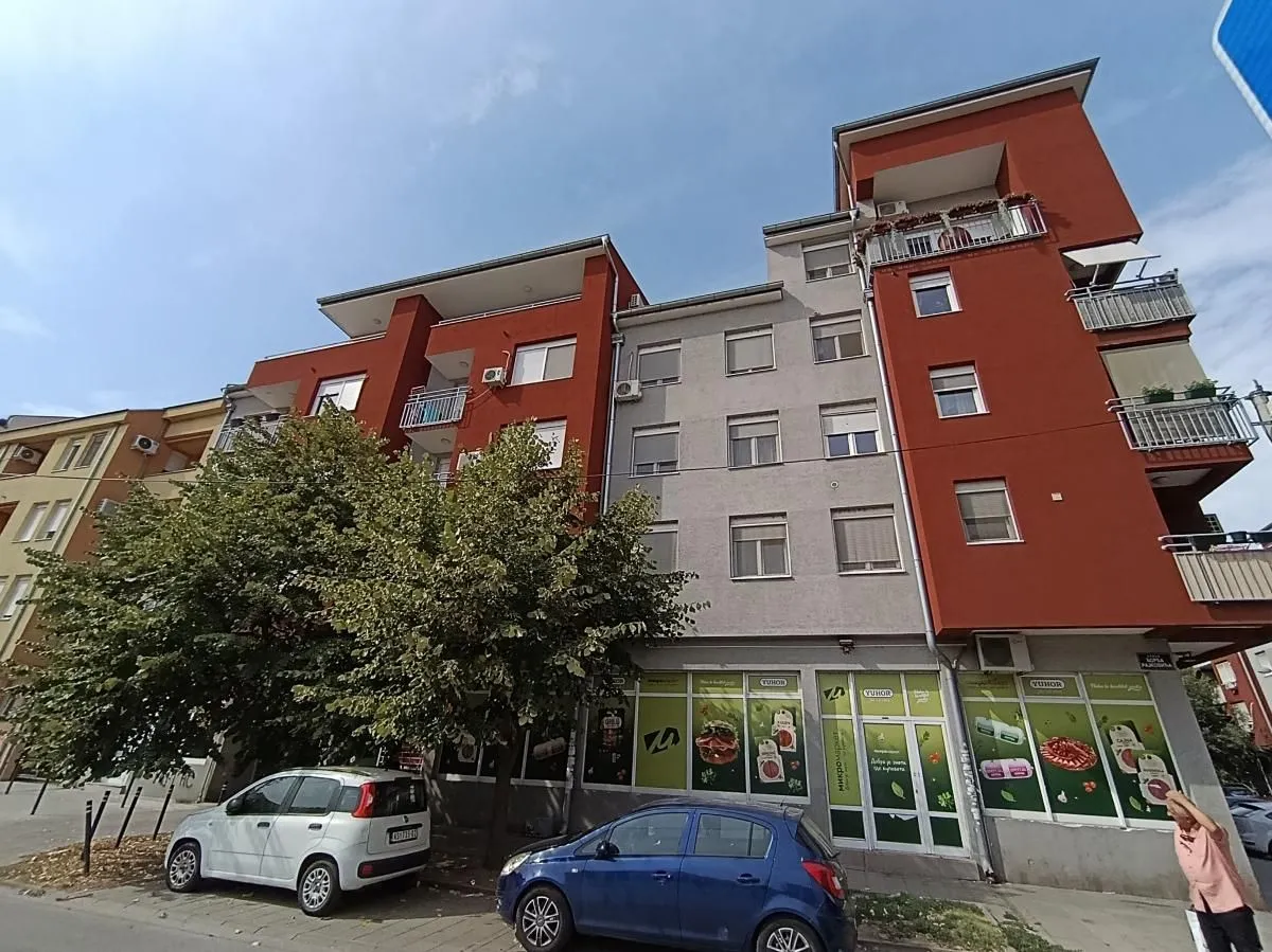 Pogled na spoljašnjost stambene zgrade sa poslovnim prostorom u prizemlju.
