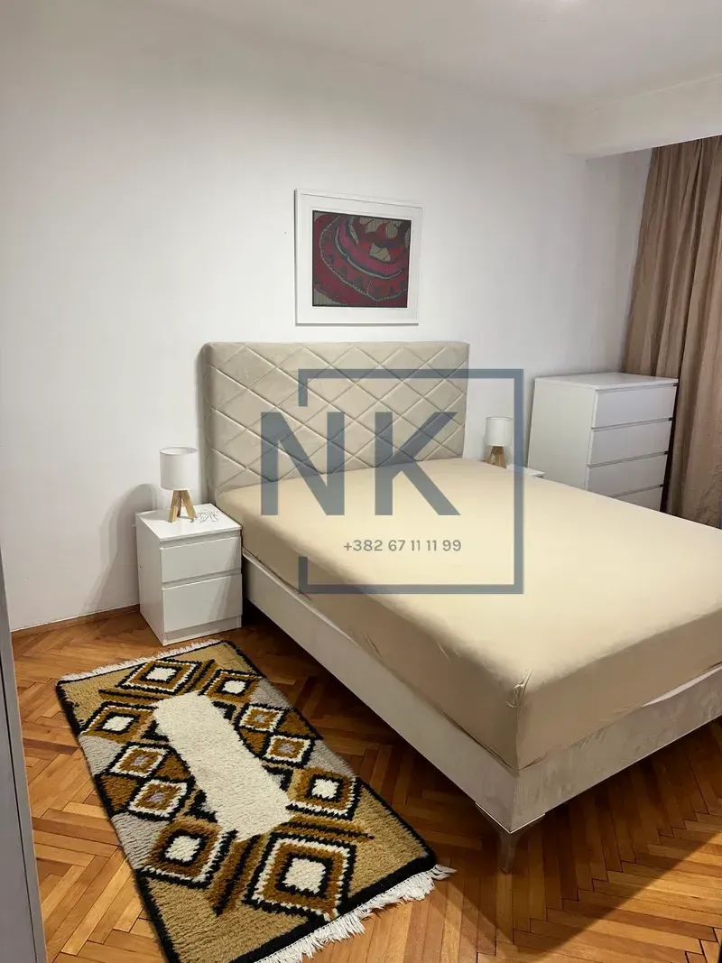 Furnished bedroom with a double bed, bedside tables, and parquet flooring.