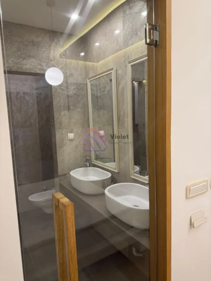 Moderne kupatilo sa dva umivaonika, ogledalima i tuš kabinom.