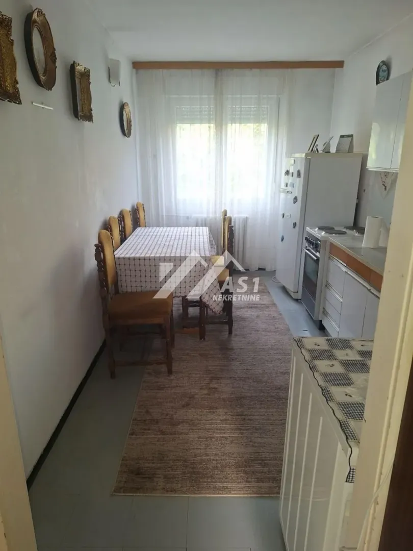 Kuhinja sa trpezarijskim stolom i stolicama.