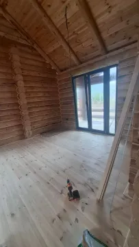 Interior of an unfinished log cabin with wooden floors and a large window. - image 15
