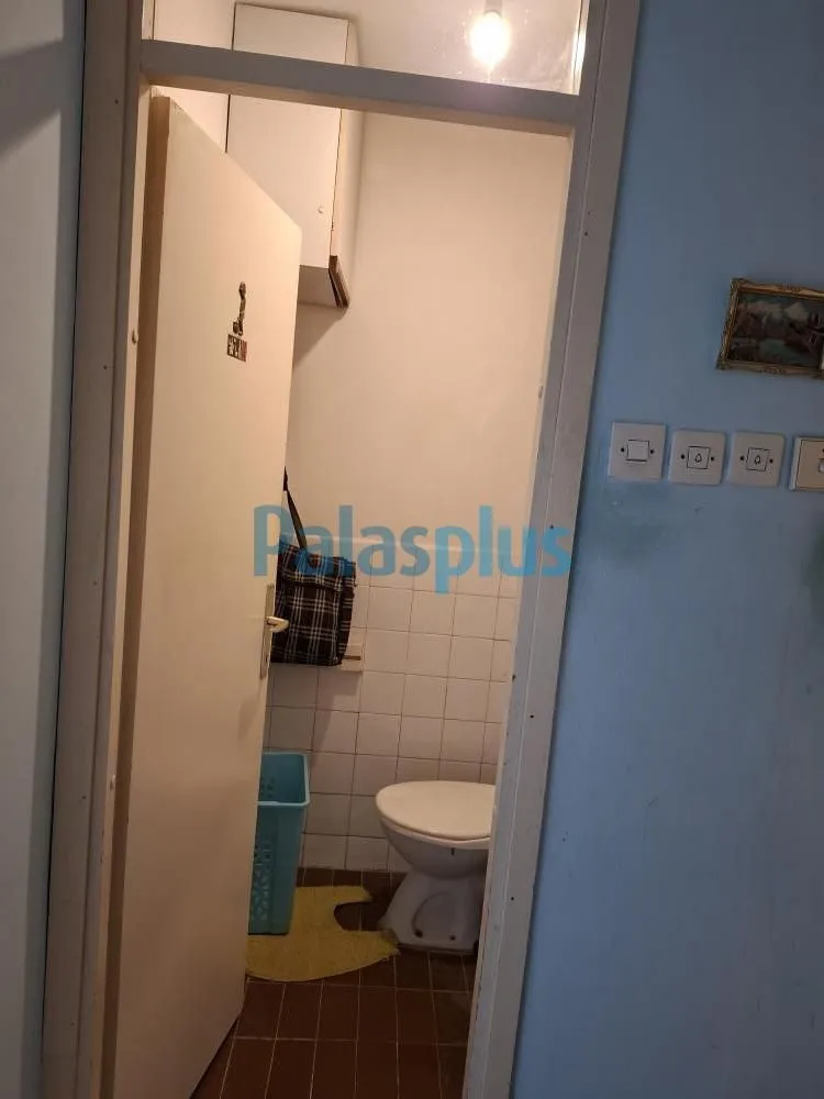 Pogled iz hodnika na manje kupatilo sa WC šoljom.