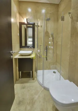 Kupatilo obloženo bež pločicama sa tuš kabinom, umivaonikom i WC šoljom. - image 17