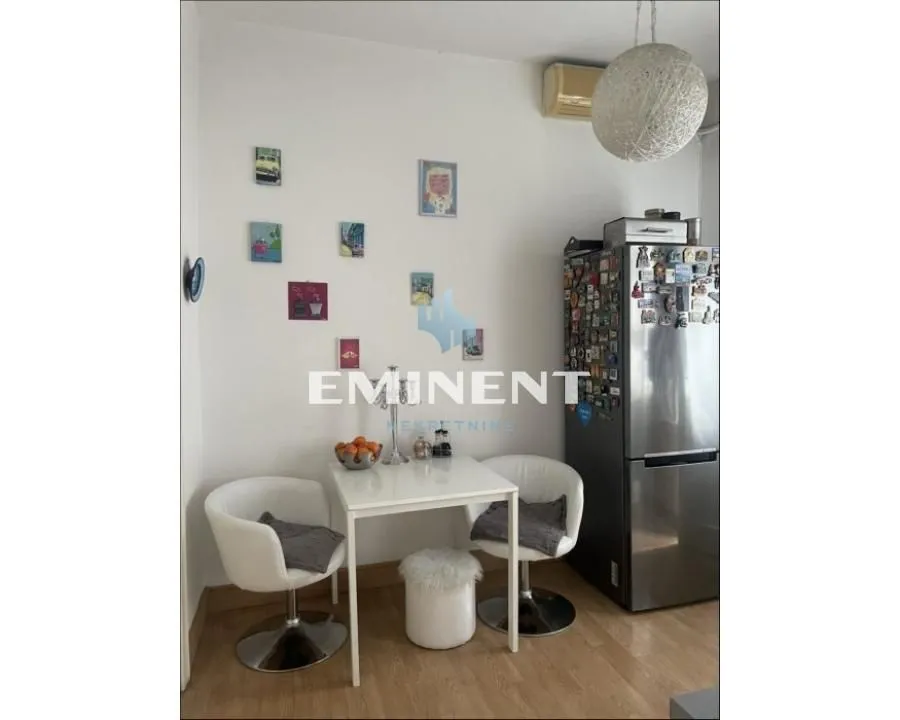 Small dining area with a table, chairs, and refrigerator.