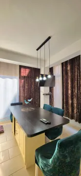 Dining room with a large table, green chairs, and a pendant chandelier. - image 4