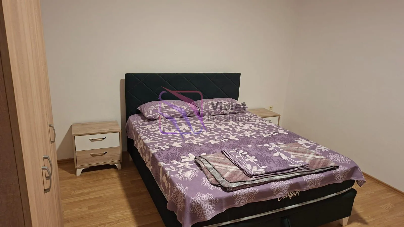 Furnished bedroom with a double bed, bedside tables, and a wardrobe.