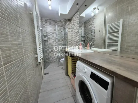 Modern bathroom with a walk-in shower, washbasin, and washing machine. - image 7