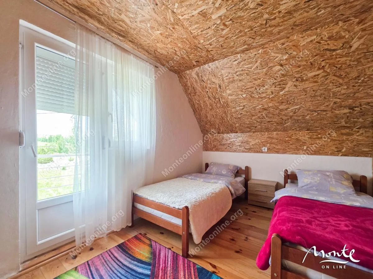 Potkrovlje opremljeno sa dva kreveta i izlazom na balkon.